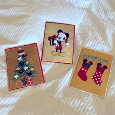 three christmas cards with mickey mouse and stocking around the tree on a white sheet