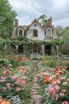 a house with lots of flowers in front of it and a pathway leading to the door