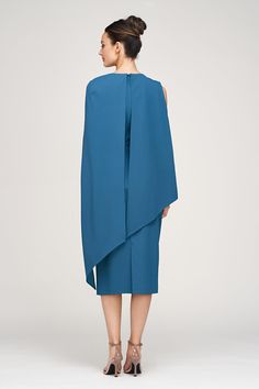 the back view of a woman wearing a blue dress with one shoulder draped over her shoulders