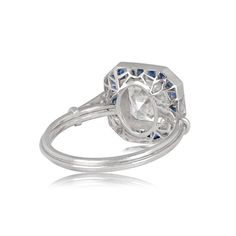 a white gold ring with an oval cut diamond and blue sapphires on the side