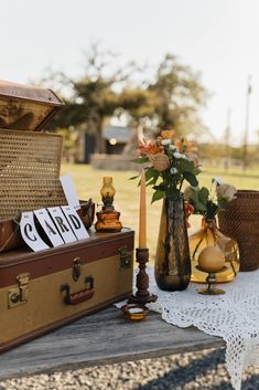 an open suitcase sitting on top of a wooden table next to flowers and other items