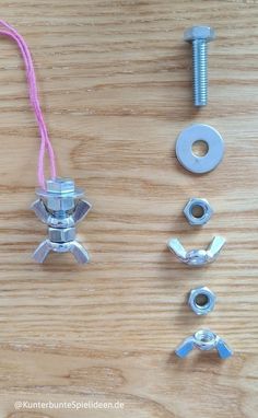 an assortment of screws and nuts on a wooden surface with pink string attached to them