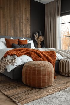 a bedroom with a large bed and two foot stools in front of the window