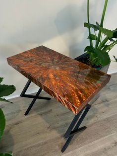 a wooden table sitting on top of a hard wood floor next to a potted plant