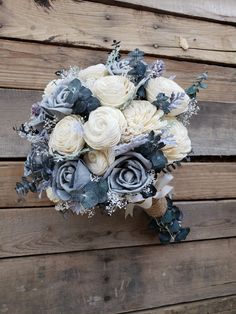 a bridal bouquet with white and blue flowers on a wooden background, ready to be used as a wedding bouquet