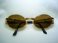 "An intoxicating amalgam of original atypical design and top optical technology, produced by prestigious yet elusive \"Castellani-Italy \", a genuine Gold Bonanza, much sought after by collectors and wearers alike. Produced in the 1990's by legendary designer Danilo Castellani-Italy, a rare if not unique pair of sunspecs. Hand made super heavy Gold plated metal alloy frame, sumptuously embellished with Platinum plated sculptural Egyptian motifs (King Tut's head), complemented with jet black acet Gold Formal Sunglasses With Anti-reflective Coating, Retro Gold Metal Sunglasses, Luxury Vintage Gold Sunglasses, Sunglasses Oval, Vintage Gold Sunglasses With Metal Frame, Egyptian Motifs, Vintage Black Shield Sunglasses With Anti-reflective Coating, King Tut, Sports Sunglasses