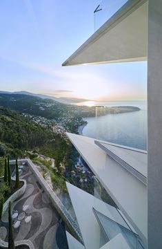 an aerial view of the ocean and mountains from a building with glass walls that overlook it