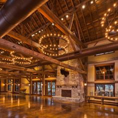 the inside of a large building with lights hanging from it's ceiling and wood beams