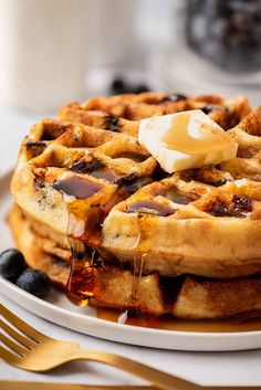 a stack of waffles sitting on top of a white plate with syrup and butter