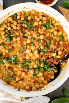 a white bowl filled with chickpeas and spinach on top of a table