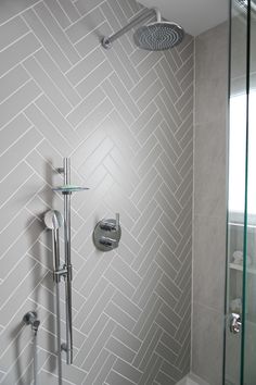 a bathroom with a shower head, hand held shower faucet and tiled walls