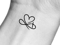 a heart and cross tattoo on the back of a white leather armband with black ink