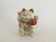 a ceramic cat figurine holding two kittens