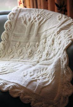 a white crocheted blanket sitting on top of a couch next to a window