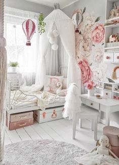 a bedroom decorated in pink and white with flowers on the wall, bed canopy over it