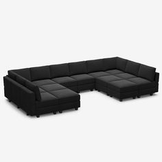 a black sectional couch sitting on top of a white floor next to a chair and ottoman