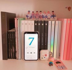 a phone sitting on top of a white desk next to books and other items in front of it