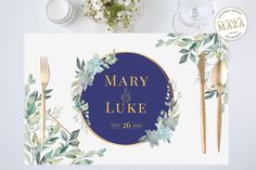 a wedding place card with greenery and gold cutlery next to silverware on a white table