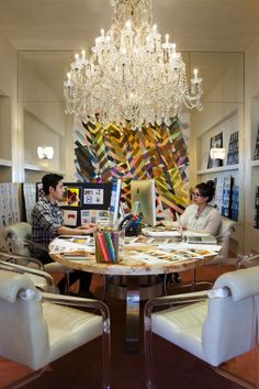 two people sitting at a table in front of a chandelier with pictures on it