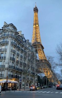 the eiffel tower lit up at night in paris, france with cars passing by