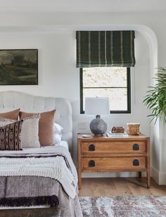 a bed room with a neatly made bed next to a window