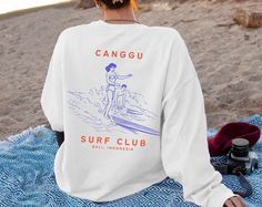 Surf Sweatshirt Oversize, Bali Surfing Club Shirt, Sweater Gift for Surfer, Retro Graphic Crewneck, Aesthetic Clothing for Her Cosy Jumper 🌊ABOUT THIS SWEATSHIRT🌊 "CANGGU SURF CLUB" design printed on the back. SIZE UP OR SIZE DOWN ∙ Sweatshirt is UNISEX and runs slightly large for ladies (size up 1-3 sizes for a loose boyfriend style, size normally or down a size for a more fitted style) - see size guide on listing images ∙ 50% cotton, 50% polyester blend fabric ∙ Colours may vary based on your monitor or screen display --- HOW TO ORDER --- 1) Choose the listing/design 2) Choose your shirt style, colour and size 3) Enter your Text/Design in the Personalization Box (If applicable) 4) Choose Your Quantity as much as you want. 5) Click add to cart. You can go back and follow the same steps White Screen Print Sweatshirt For Summer, White Relaxed Fit Sweatshirt For Beach, White Long Sleeve Sweatshirt For Beach, Surfer Sweatshirt, Surf Sweatshirt, Crewneck Aesthetic, Bali Surf, Surfer Print, Sweat Sets