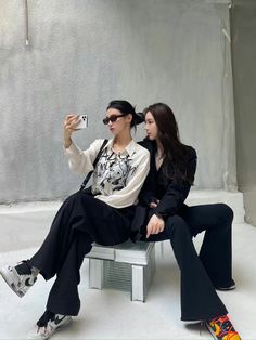 two women sitting on a bench taking pictures