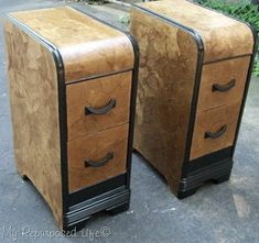 two wooden drawers sitting next to each other on top of a street side walk with trees and bushes in the background