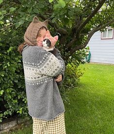 a woman holding a small dog in her arms and wearing a hat on top of her head