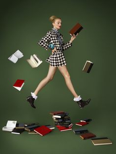 a woman is jumping in the air with books all around her