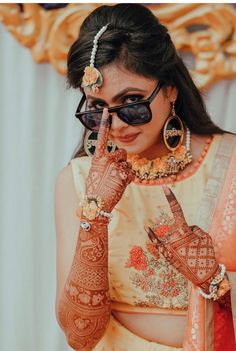 a woman with henna on her hand and holding up the fingers to her face