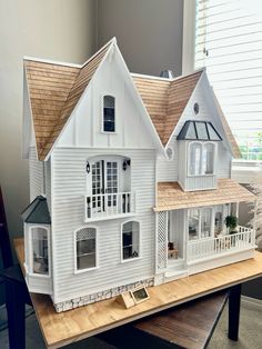 a white doll house sitting on top of a wooden table