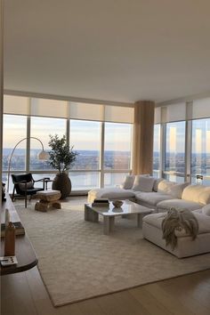 a living room filled with furniture and large windows overlooking the cityscape in the distance