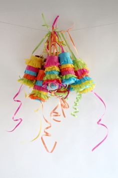 colorful streamers hanging from the ceiling in front of a white wall with ribbons on it