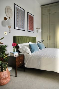 a bed sitting in a bedroom next to two framed pictures on the wall above it