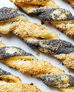 sesame seed rolls are lined up on a white plate with sesame seeds in the middle