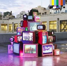 there are many tvs stacked on top of each other in front of a building