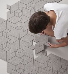 a man that is kneeling down next to a tile flooring pattern on the wall