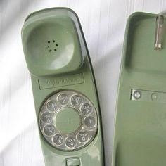 an old green phone sitting on top of a white sheet