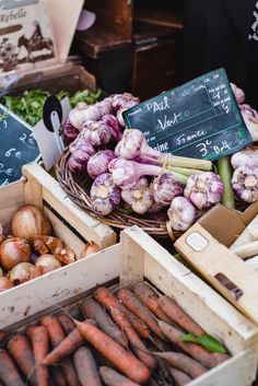 several baskets filled with lots of different types of vegetables next to boxes full of carrots