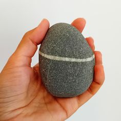 a hand holding a rock with a white line on it