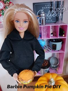 a barbie doll is holding a pumpkin pie