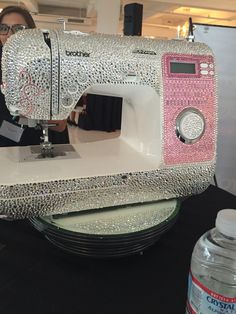 a woman standing next to a white and pink sewing machine on top of a table