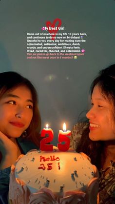 two women sitting next to each other in front of a cake with candles on it