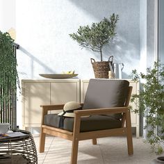 a wooden chair sitting on top of a patio next to a potted plant