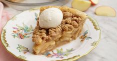 a slice of apple pie with ice cream on top sits on a flowered plate