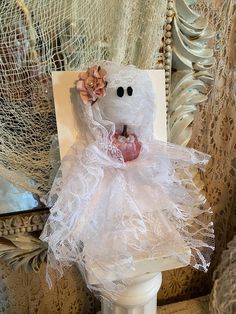 a white teddy bear sitting on top of a wooden chair next to a lace curtain