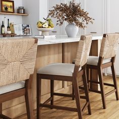 a kitchen bar with four stools and a vase filled with flowers on the counter