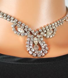 This is a lovely vintage choker from the 1950s.  The main part of the necklace is made up of a band of clear, sparkly rhinestones set in silver tone metal.  In the center in the front, there is a section with 2-3 tiers of small rhinestones surrounding larger round and marquise cut rhinestones.  The band of the necklace has small spaces between the rhinestones, and the necklace closes with a hook that can slide between any of the rhinestones.  SIZING The necklace is 15 inches long and this can be adjusted as short as you need.     CONDITION This necklace is in excellent vintage condition. Please feel free to ask any questions about this item before making your purchase.  I have MANY items in my store, so shop around a bit.  Other ACCESSORIES in my store: http://www.etsy.com/shop/HepCatCloth Vintage Rhinestone Choker Jewelry, Vintage Crystal Rhinestone Choker Necklace, Vintage Rhinestone Choker Necklace, Vintage Rhinestone Crystal Choker Necklace, 50s Jewelry, Luxury Vintage Rhinestone Necklace, Vintage Metal Rhinestone Necklace With Chain, 1950s Jewelry Rhinestone, Vintage Rhinestone Adjustable Necklace