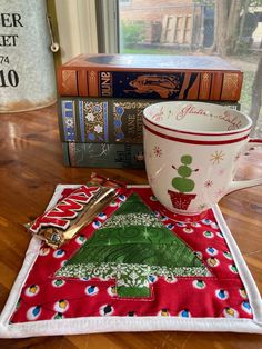 a coffee cup sitting on top of a table next to a stack of books and a mug